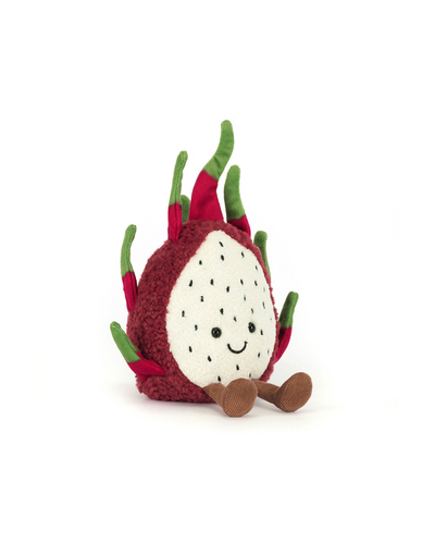 The Jellycat Amuseables Dragon Fruit plush sits upright on brown legs, with a white face dotted with black seed-like spots, a smiling expression, and green leaf-like accents. Filled with soft polyester fibers, it's pictured against a white background.