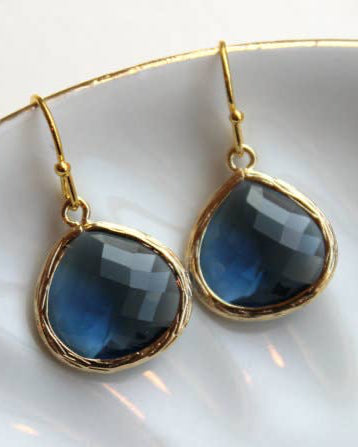 A pair of Large Sapphire Navy Blue Earrings featuring faceted dark blue gemstones and gold filled earwires, elegantly displayed on a white dish.