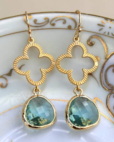 Prasiolite Green Clover Quatrefoil Earrings - Gold: Gold plated dangle earrings with quatrefoil shapes and faceted prasiolite green gemstones, displayed on a decorative plate. Gift box included.