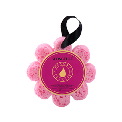 The Spongelle Wild Flower - Bulgarian Rose is a pink, flower-shaped bath sponge complete with a black ribbon handle that provides an exfoliating massage experience. It boasts a purple label adorned with gold text and designs, making it as delightful as colorful flowers.