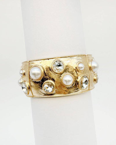 The Hammered Stretch Bangle with Pearls and Clear Crystals - Gold features a wide, uneven hammered gold surface accented with scattered round white pearls and clear crystals.
