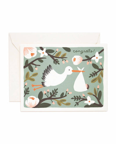 The Congrats Stork - Card features a stork carrying a bundle, surrounded by flowers and branches, with "congrats!" in the top right corner. This charming new baby card comes with an envelope behind it.