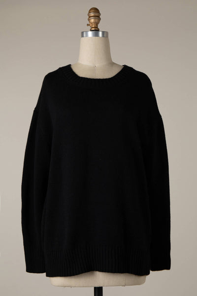 The Lyla Cable Knit Ribbed Soft Pullover Sweater in black is showcased on a dress form against a simple beige backdrop. This sweater highlights a crew neckline, long sleeves, and a relaxed fit.