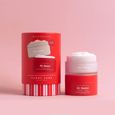 The image features the Candy Cane Body Scrub + Body Butter Holiday Gift Set by NCLA Beauty, set against a pink background. The packaging is red with white text and striped details, perfectly capturing the festive spirit.