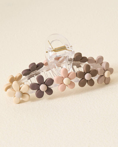 The Daisy Claw Clip - Natural is a beautiful hair accessory with a natural look, featuring small beige, brown, and pink floral decorations on its transparent edges. Set against a plain light background, it's ideal for adding subtle elegance to any hairstyle.