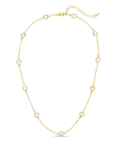 A gold-plated collar necklace with bezel-set glass crystal accents evenly spaced along a delicate chain, displayed against a white background.