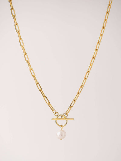 Gold-plated curb chain necklace with a toggle clasp and a single freshwater pearl centerpiece against a neutral background.