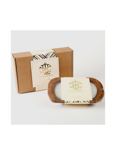 The 3 Wick Dough Bowl Candle - Italian Linen by Lux Fragrances sits in a rustic brown dough bowl, exuding charm. It comes in a cardboard box, adorned with elegant gold and black branding and a matching label, for a truly sophisticated presentation.