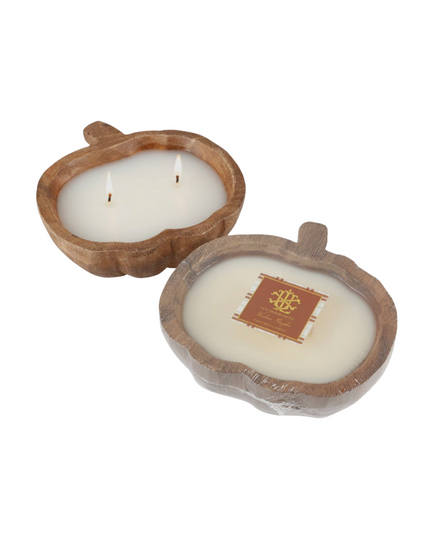 The Wooden Pumpkin Bowl Candle - Small - Fall Chai Tea features two pumpkin-shaped wooden bowls, each filled with white wax and twin wicks to capture the essence of autumn warmth. One candle is adorned with a dark label embellished with gold and white design elements and text, suggesting a delightful cinnamon chai tea fragrance. Both candles are beautifully displayed on a simple white background.